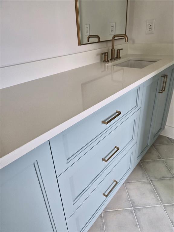 Bathroom vanity with pale blue cabinets, white countertop, and bronze faucet.