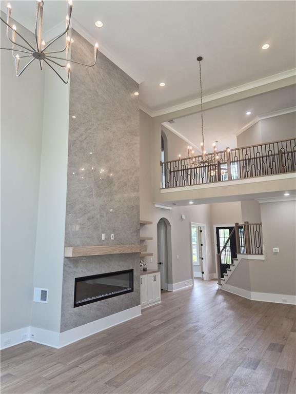 Two-story living room with a tall stone fireplace, open railing, and wood-look floors.