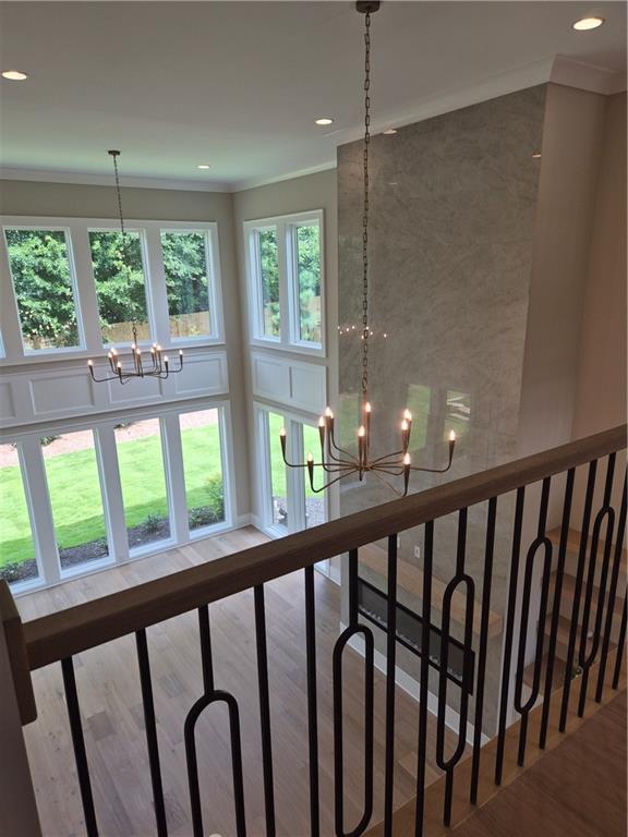 Two-story living room with a tall stone fireplace, chandeliers, and large windows.