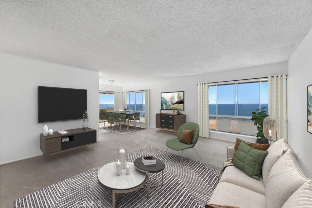 Staged living room with a green accent chair and ocean views through large windows.