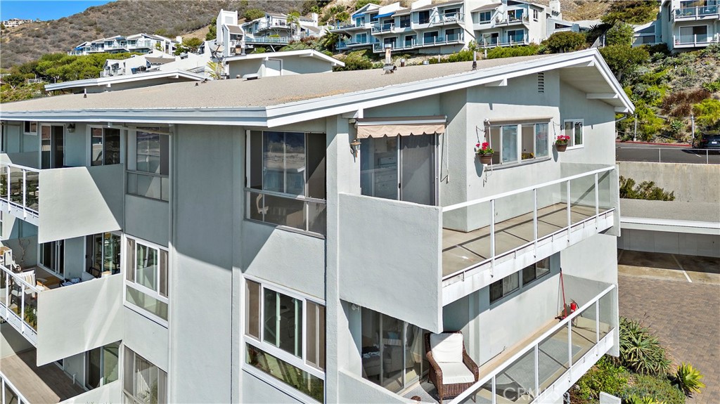 Multi-story condominium with wraparound balconies and a hillside in the background.