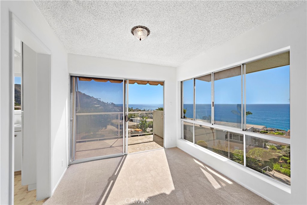 Unfurnished ocean-view room with large windows and a sliding glass door to the balcony.