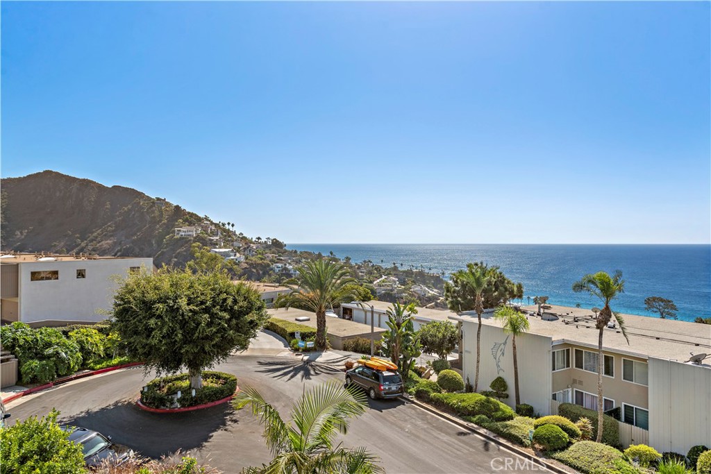 Coastal residential community with palm trees, a hillside, and a view of the Pacific Ocean.