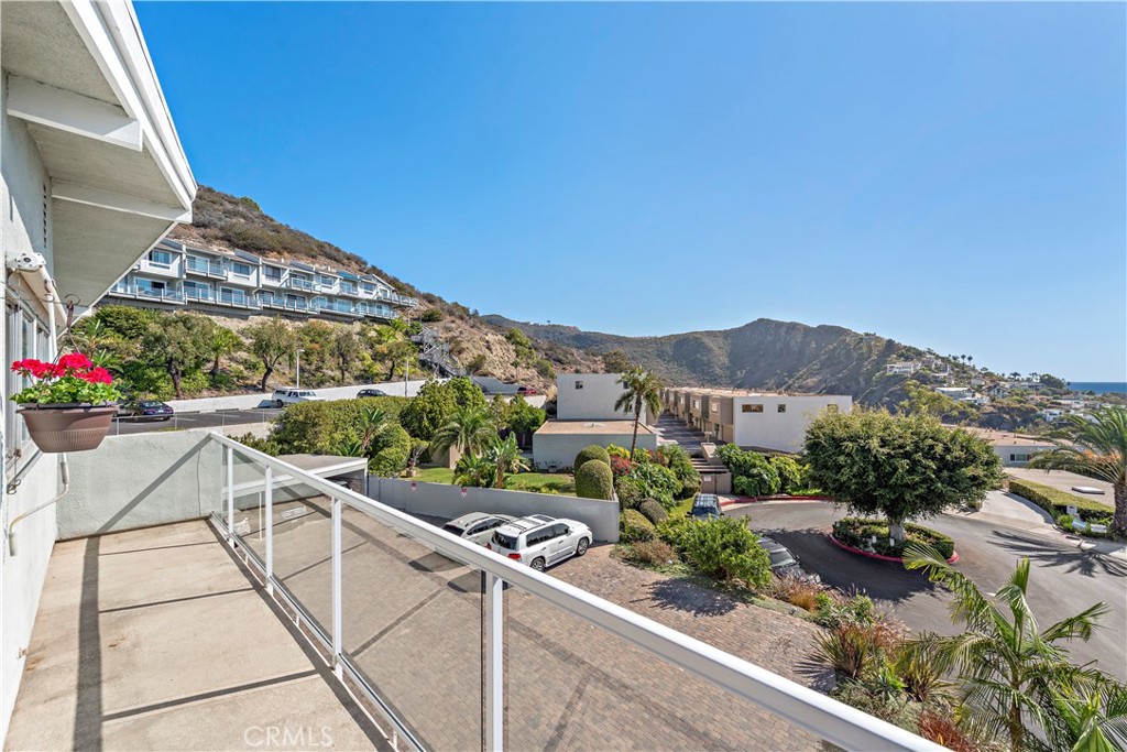 Condominium balcony overlooking landscaped grounds, neighboring homes, and dry hills.