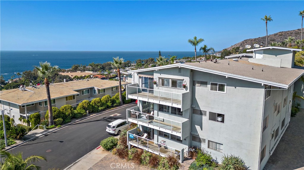 Aerial view of a coastal condominium building with balconies overlooking the ocean.