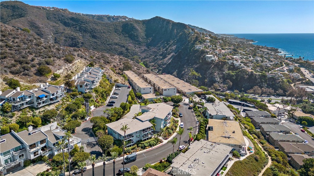 Aerial view of coastal homes between rugged hills and the Pacific Ocean.