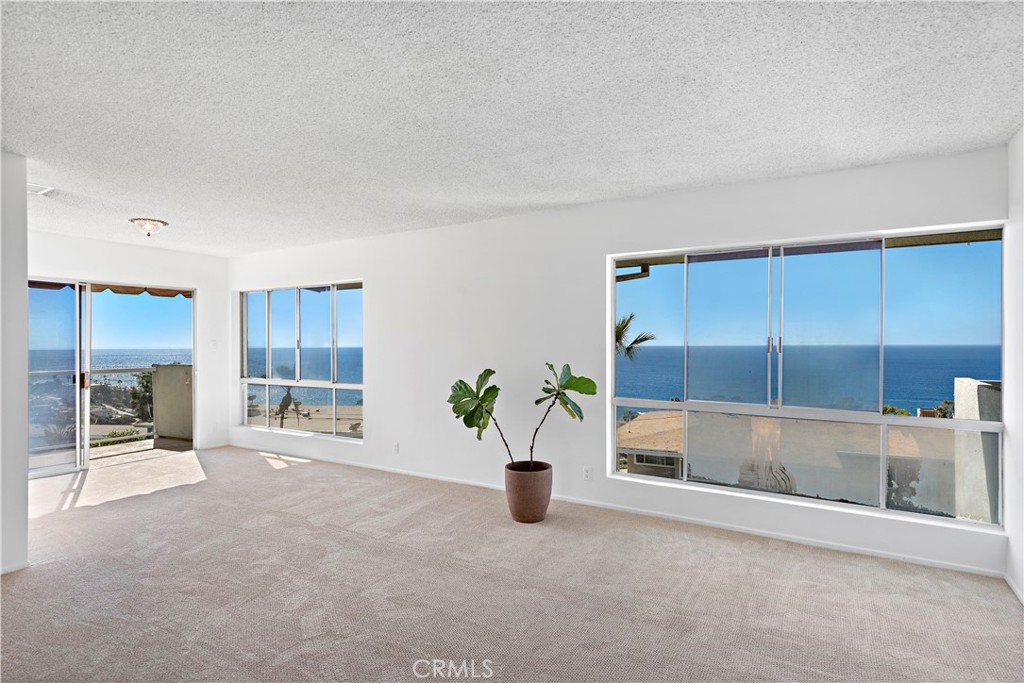 Empty living room with a potted plant and broad ocean-view windows.