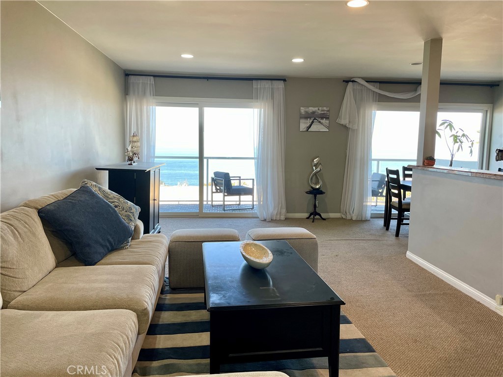 Living room with a beige sectional and sliding doors overlooking the ocean.
