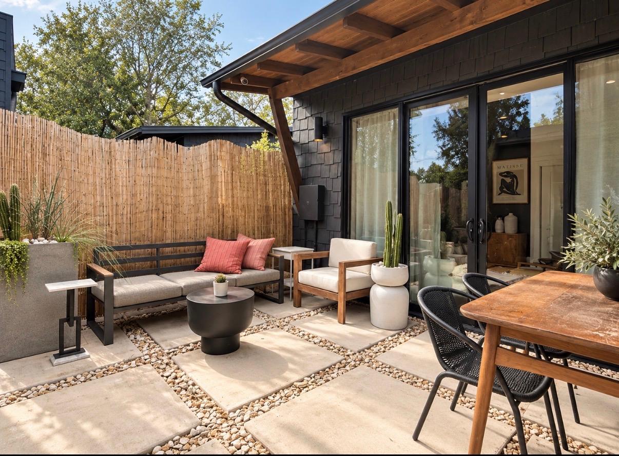 Private patio with cushioned seating, a wood dining table, potted plants, and a bamboo privacy fence.