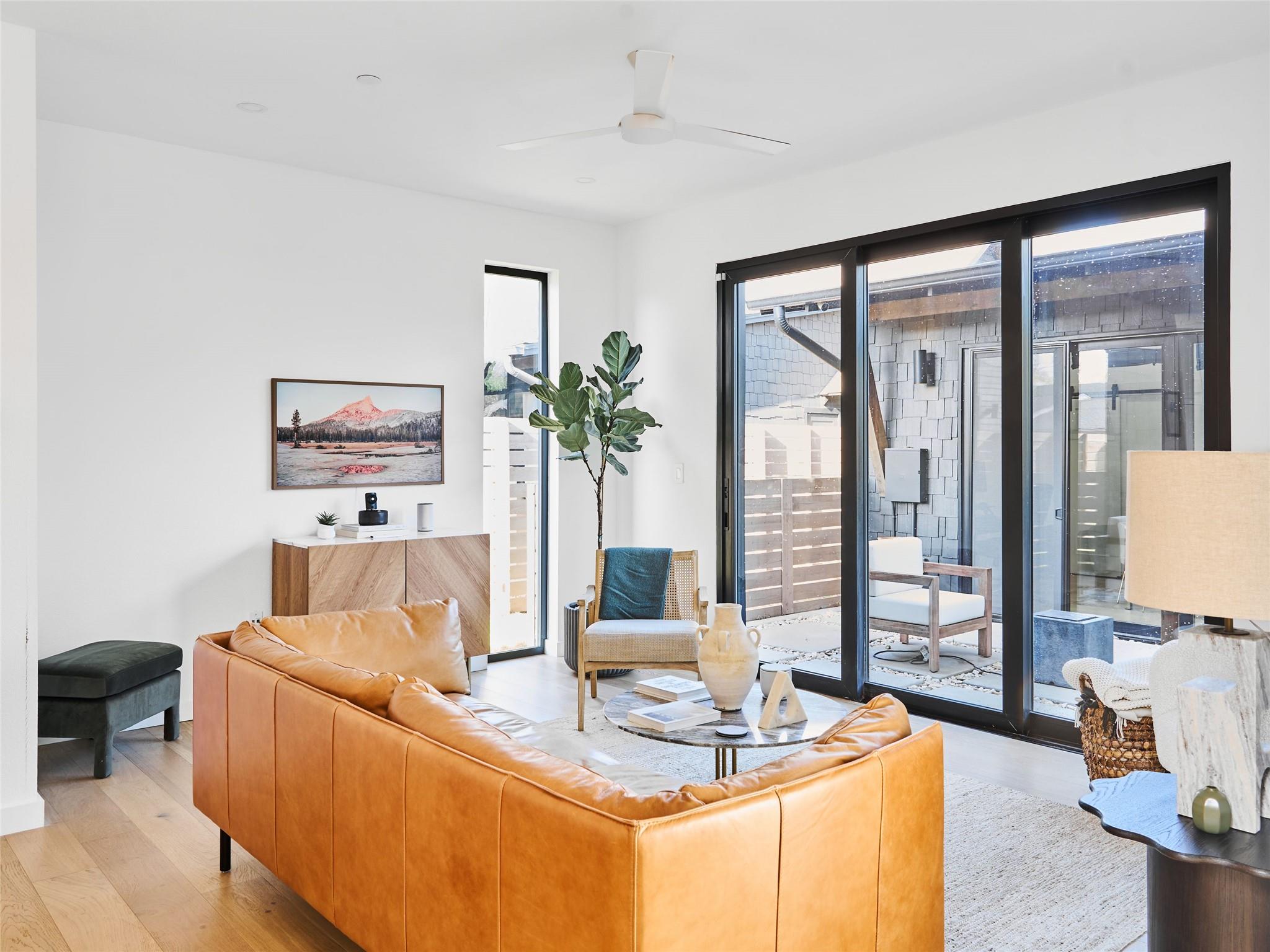 Living room with a caramel leather sectional and large sliding glass doors opening to a patio.