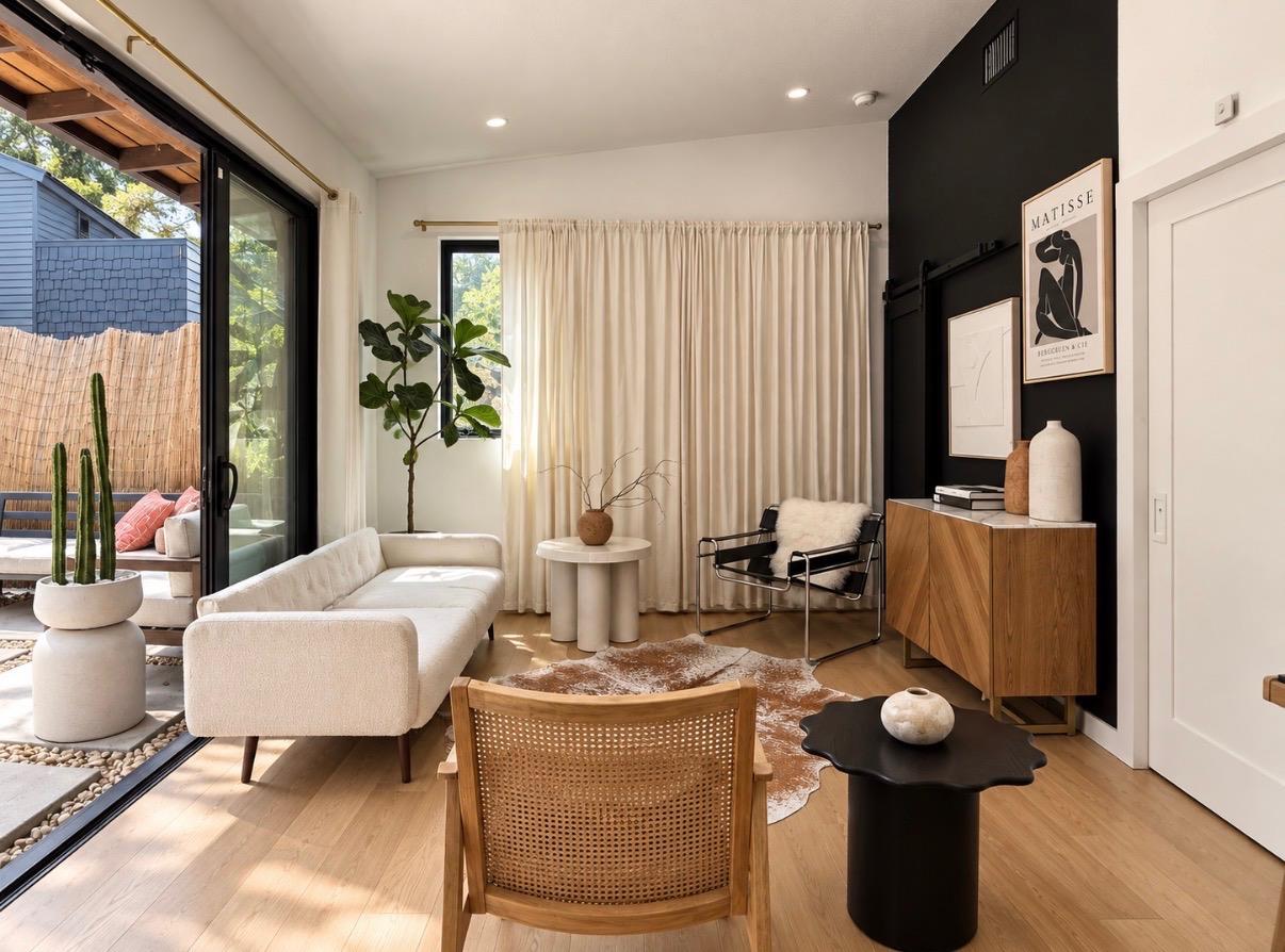 Living room with a cream sectional, black accent wall, wood floors, and sliding doors to a patio.