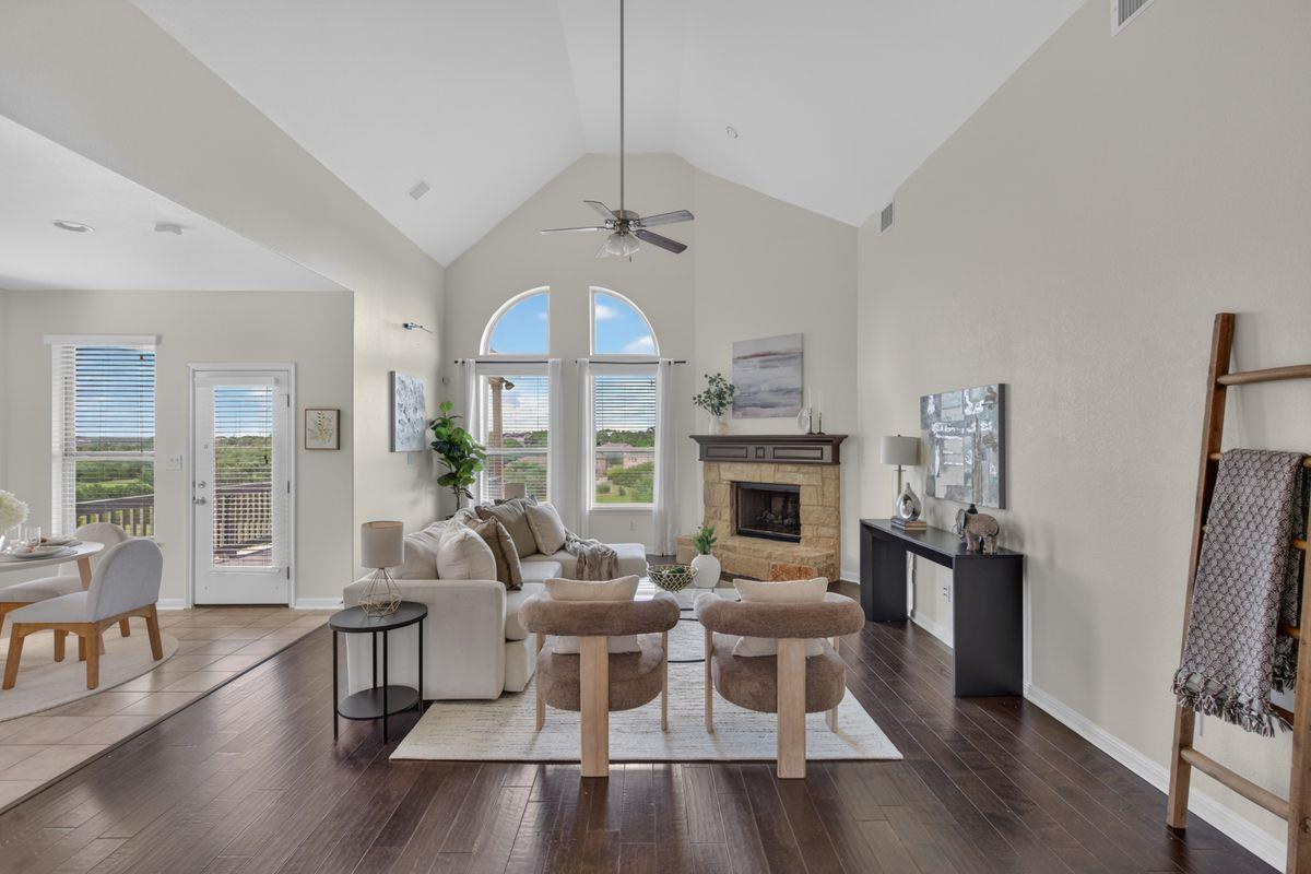 Living room with vaulted ceiling, stone fireplace, arched windows, and dark wood floors.