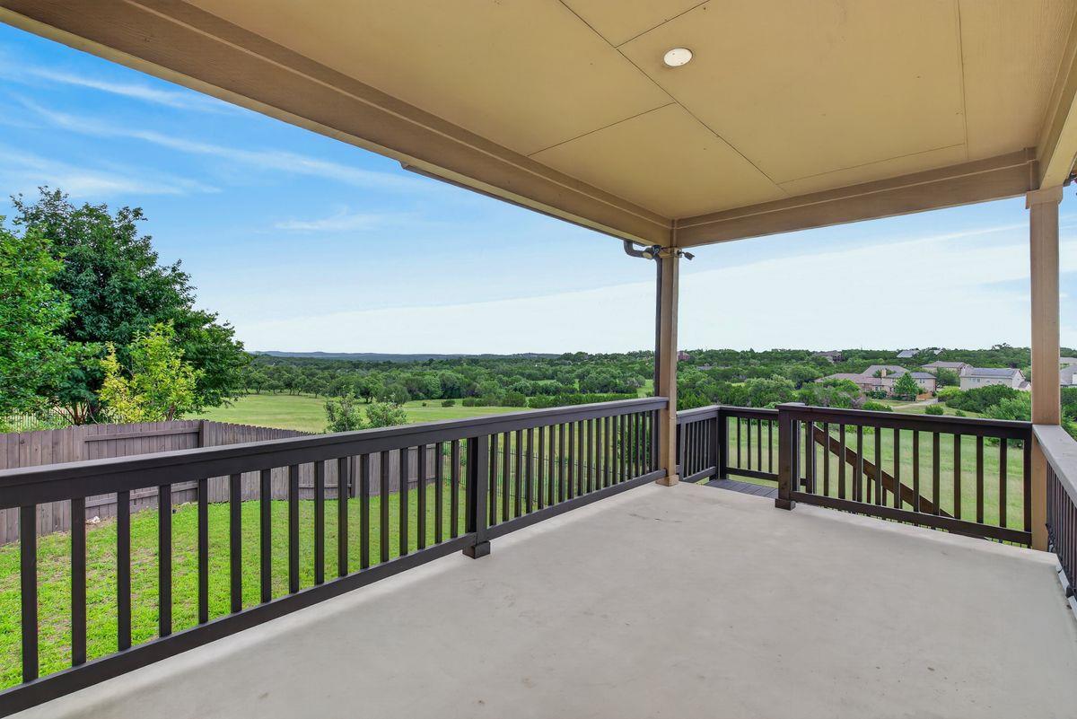 Covered patio with dark railings overlooking a green, tree-lined landscape.