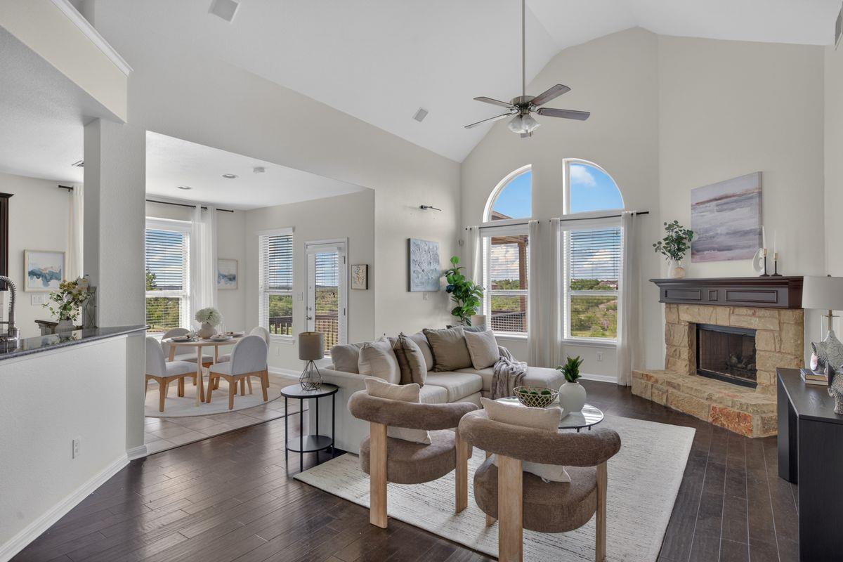 Furnished living room with a vaulted ceiling, arched windows, and a stone fireplace.