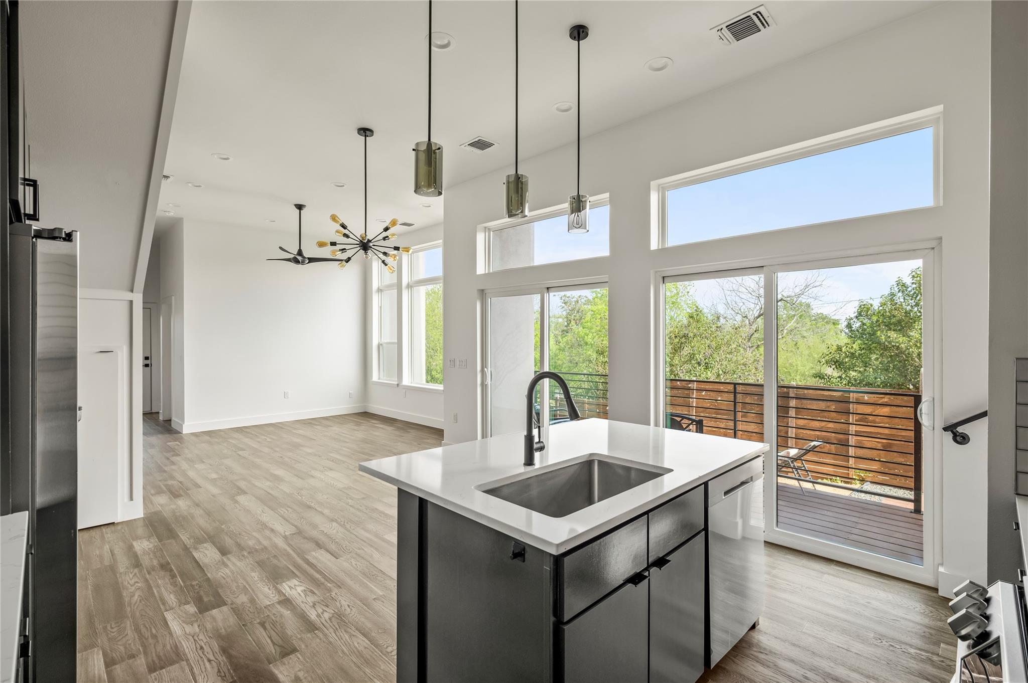 Open-plan kitchen with a large island, high ceilings, and sliding doors to a deck.