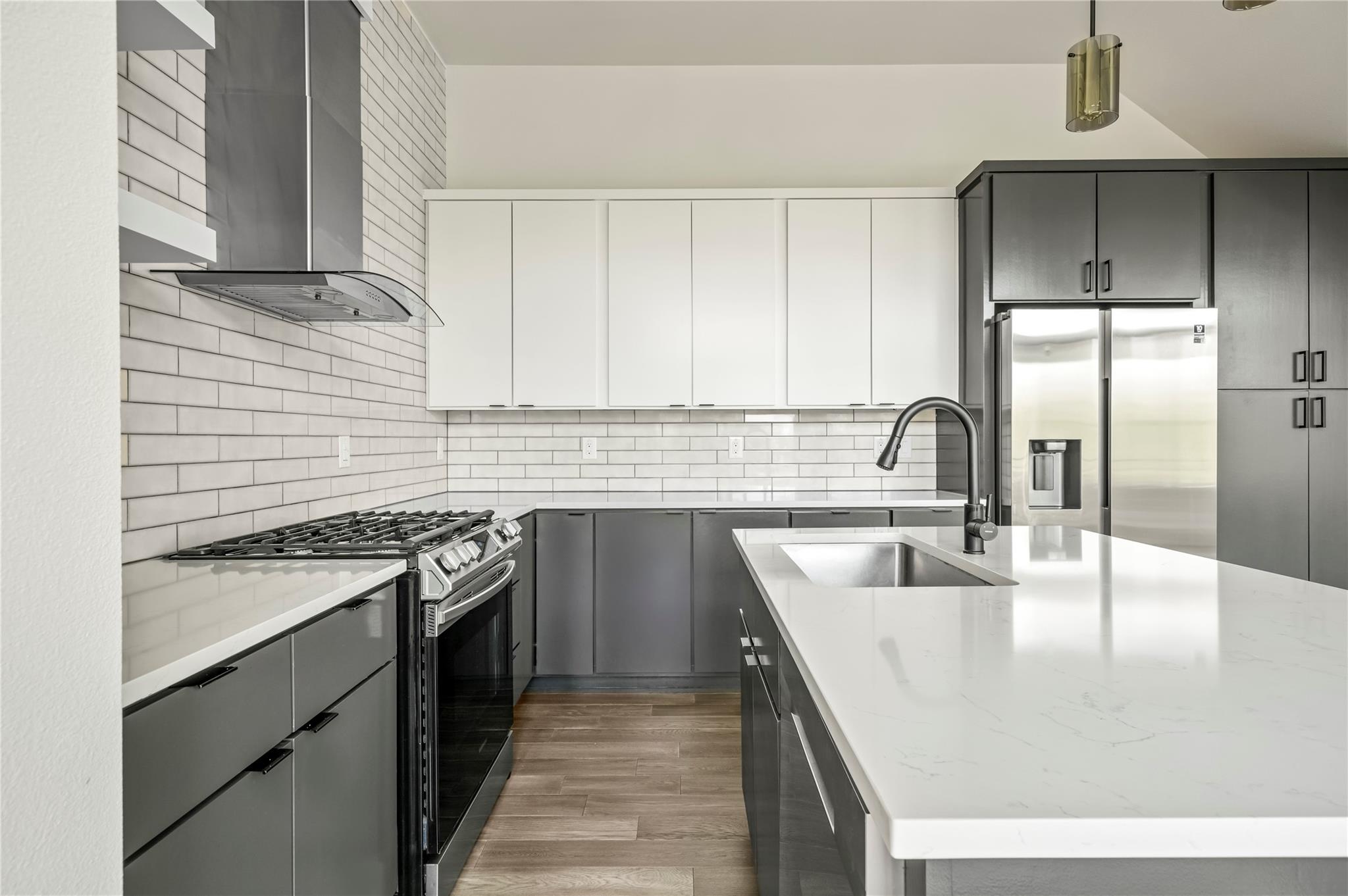 Modern kitchen with gray cabinets, stainless steel appliances, and a large white island.