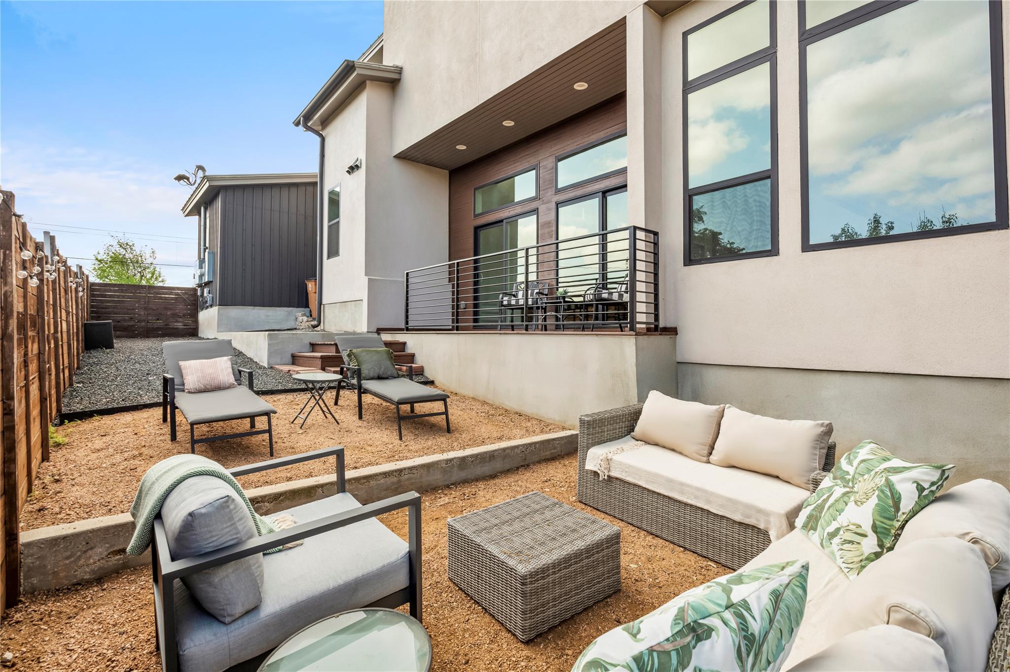 Modern home’s rear patio with a raised deck, gravel yard, and outdoor lounge seating.