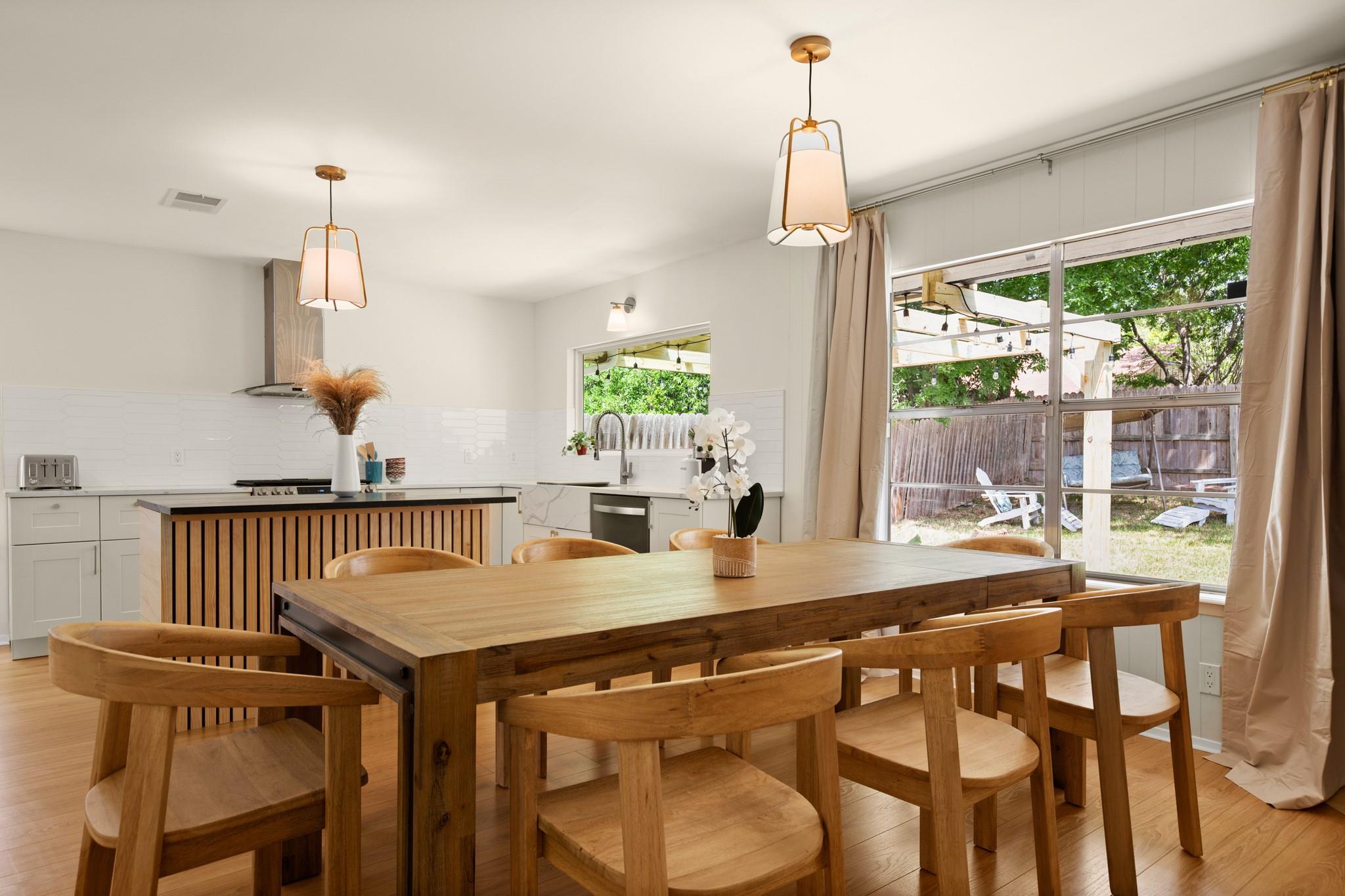 Kitchen and dining area with a wood-slat island and large table beside backyard-facing sliding doors.