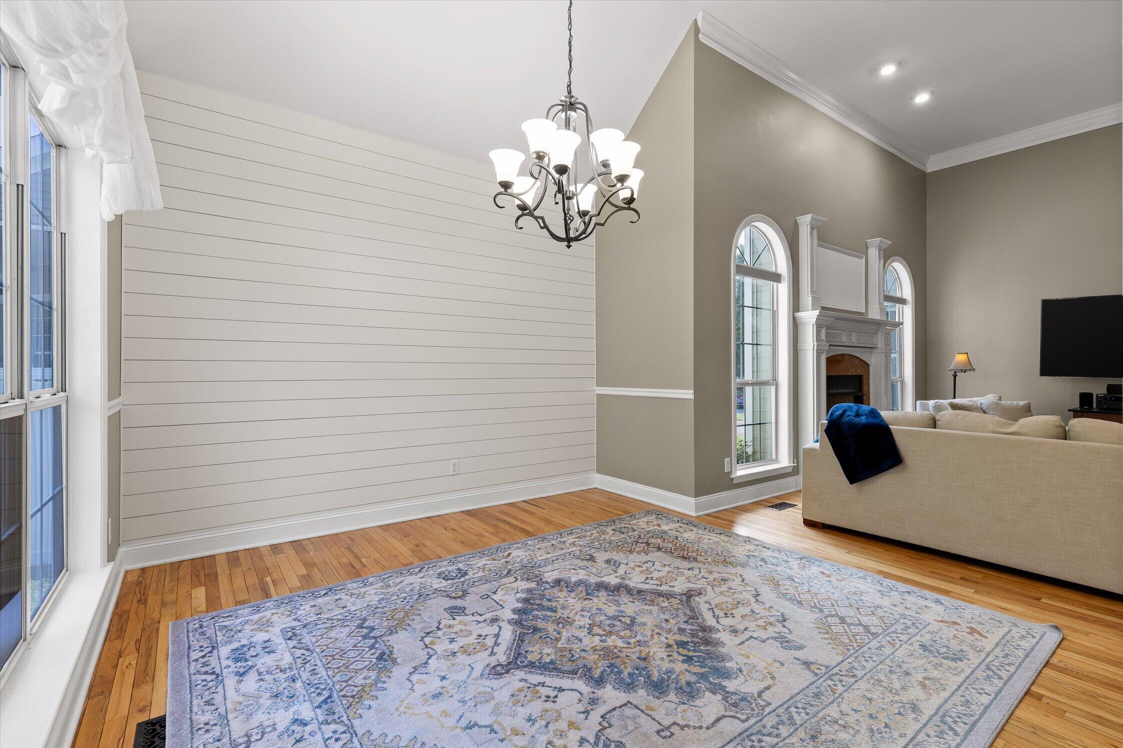 Living room with a shiplap accent wall, arched windows, fireplace, and patterned rug.