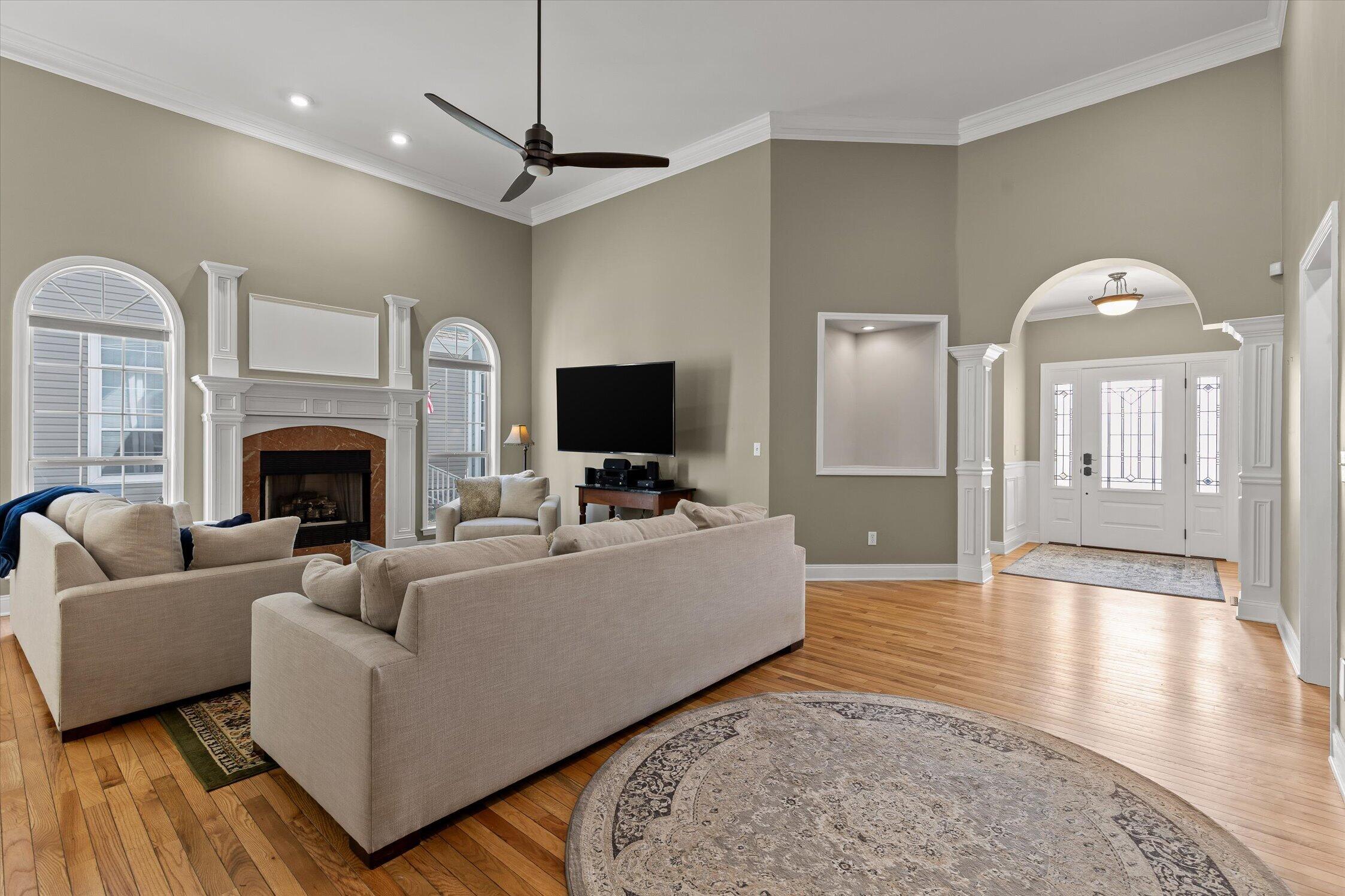 Living room with a fireplace, arched windows, hardwood floors, and an arched entryway.