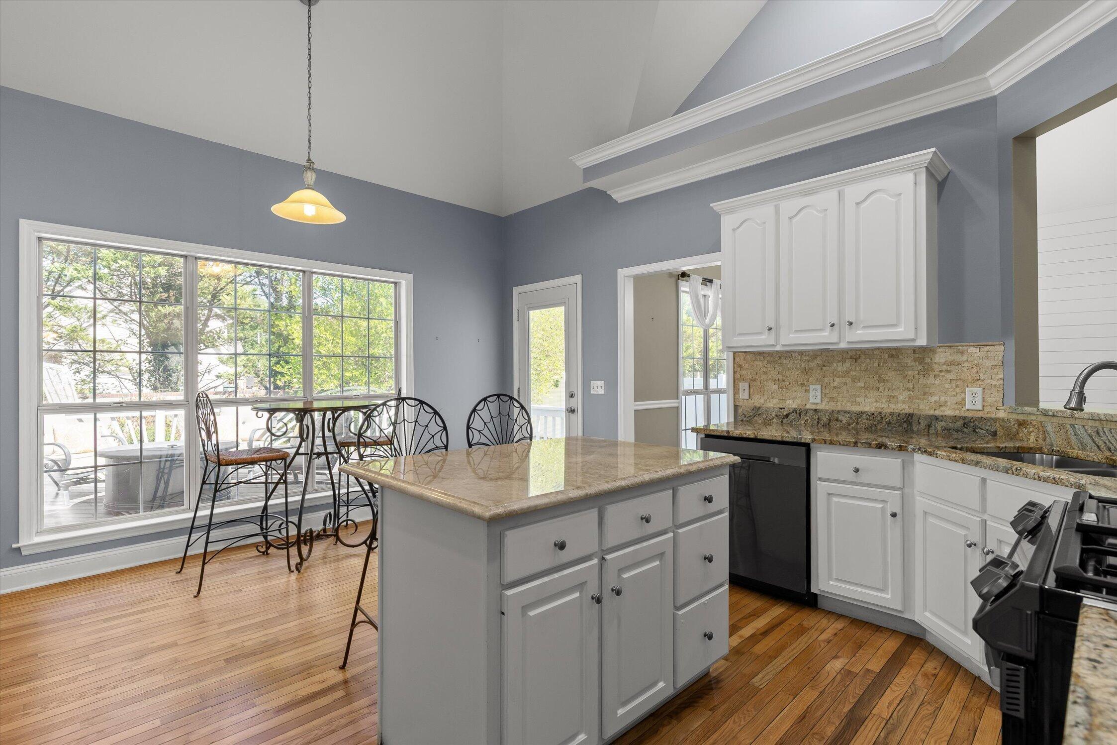 Kitchen with a granite island, white cabinetry, and a window-side dining table.