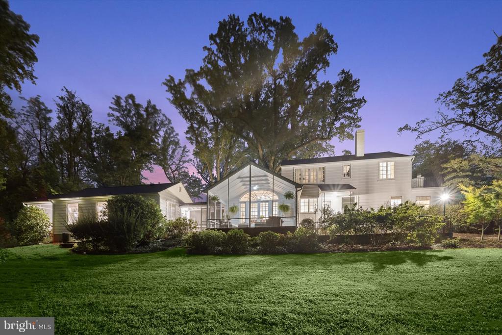 White two-story home at dusk, with a glass-gabled central section and broad front lawn.
