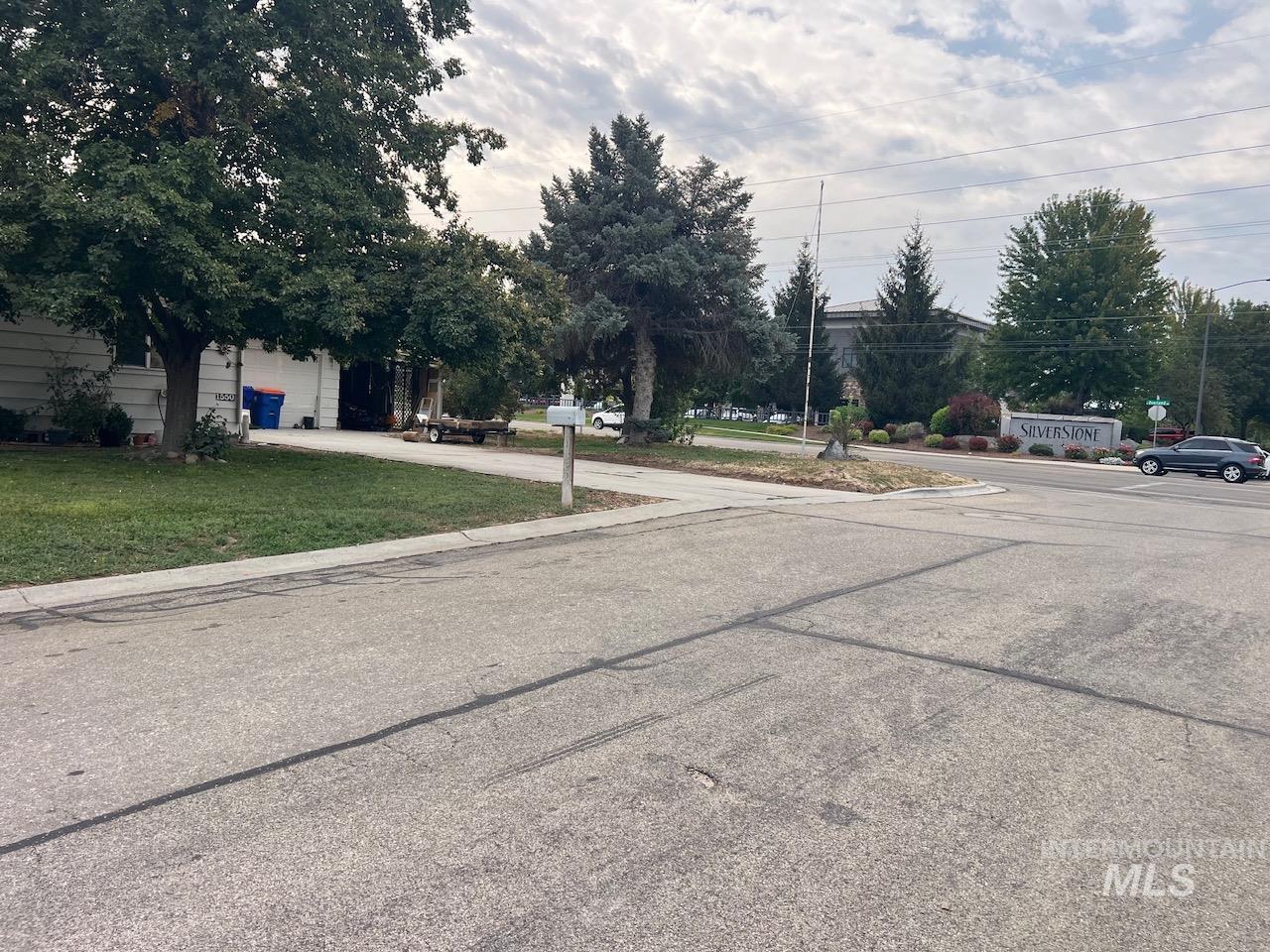 Street-side view of a shaded home with a driveway and Silverstone sign across the street.