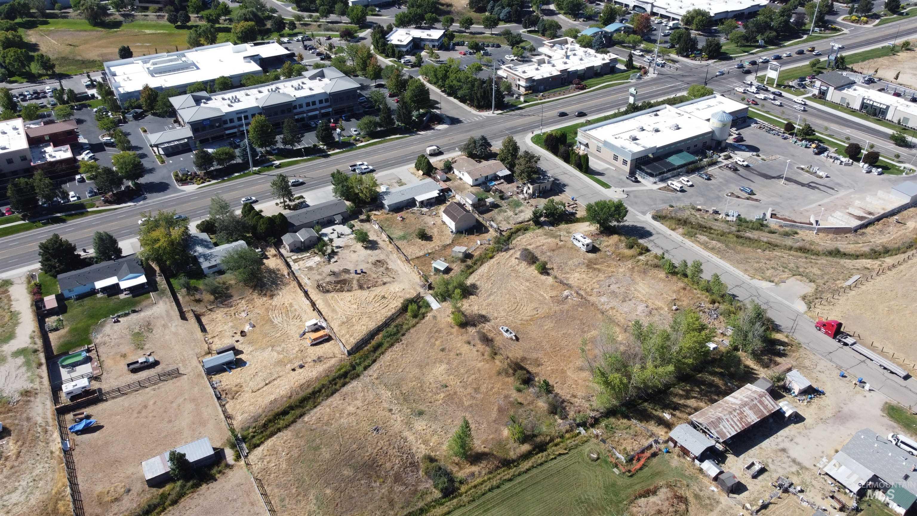 Aerial view of a dry open parcel beside commercial buildings and a multi-lane road.