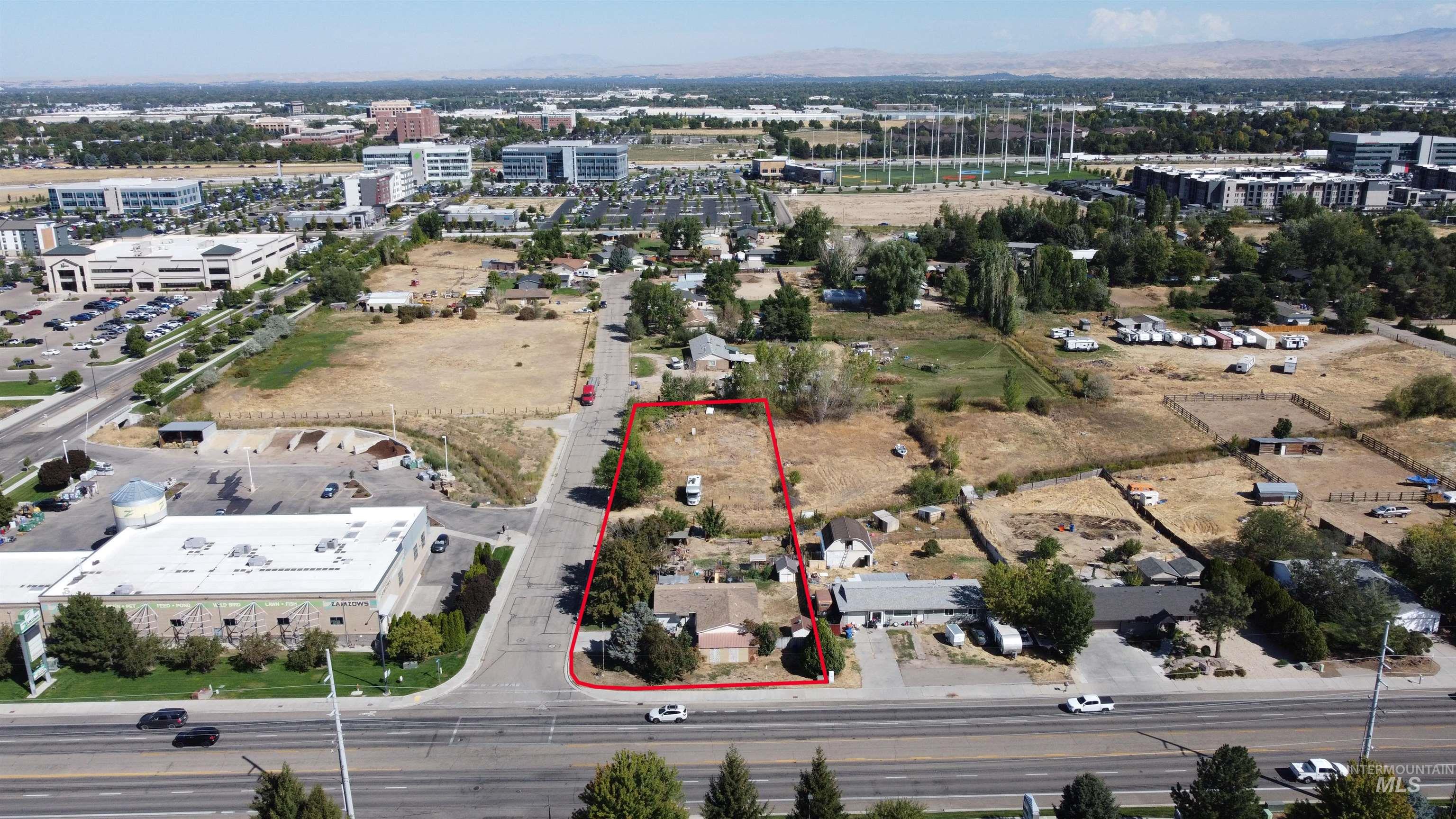 Aerial view of a red-outlined property parcel with small structures beside a road.