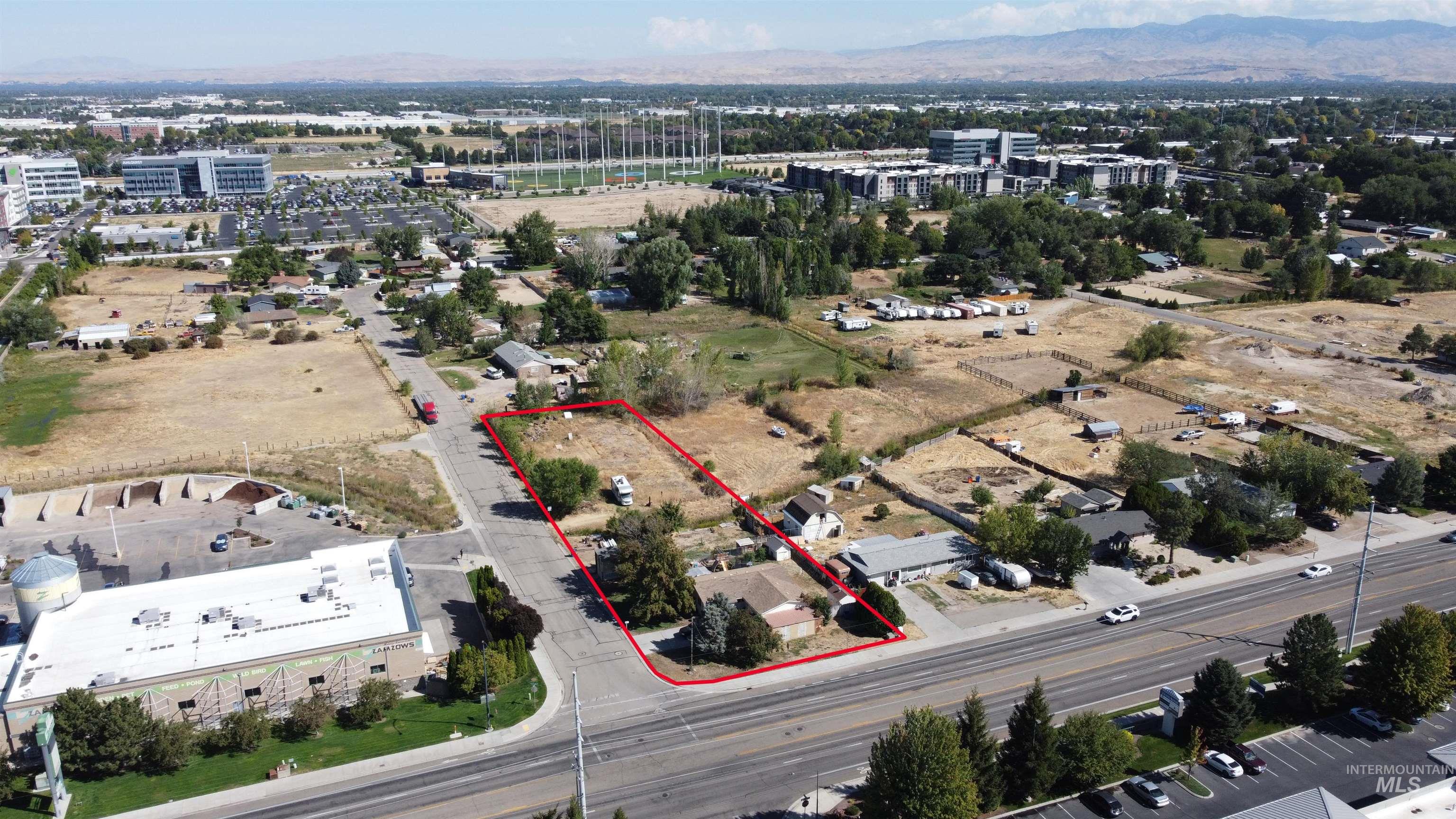 Aerial view of a mostly open parcel outlined in red, with frontage on a busy road.