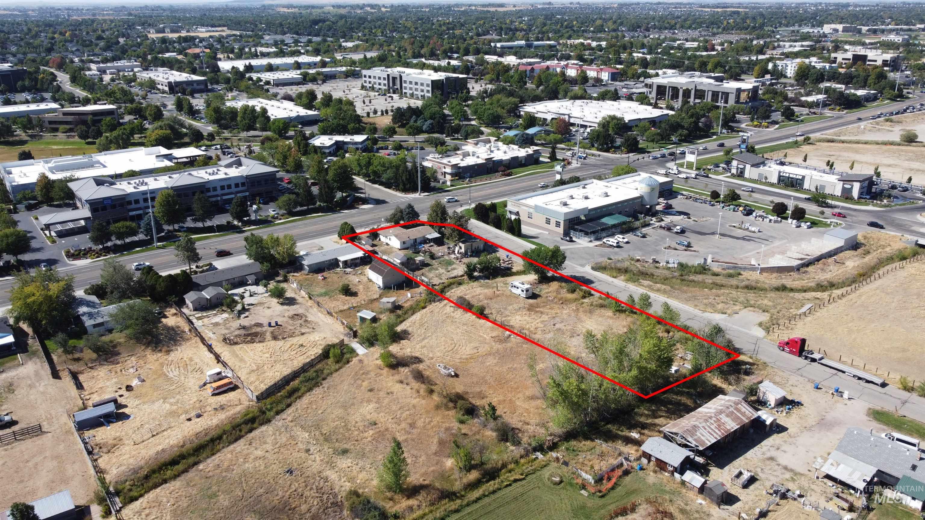 Aerial view of a dry parcel outlined in red beside roads and commercial buildings.