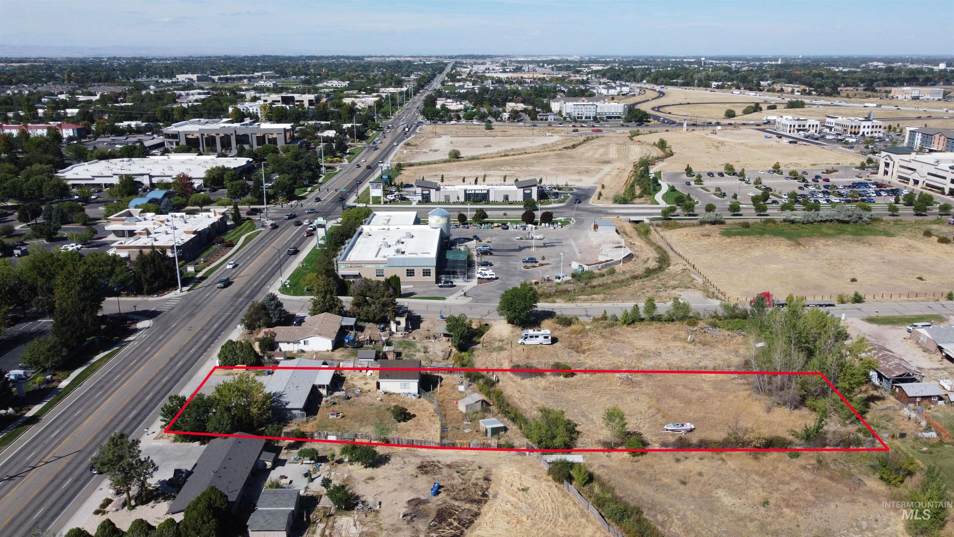 Aerial view of a dry parcel outlined in red beside a major road and commercial buildings.