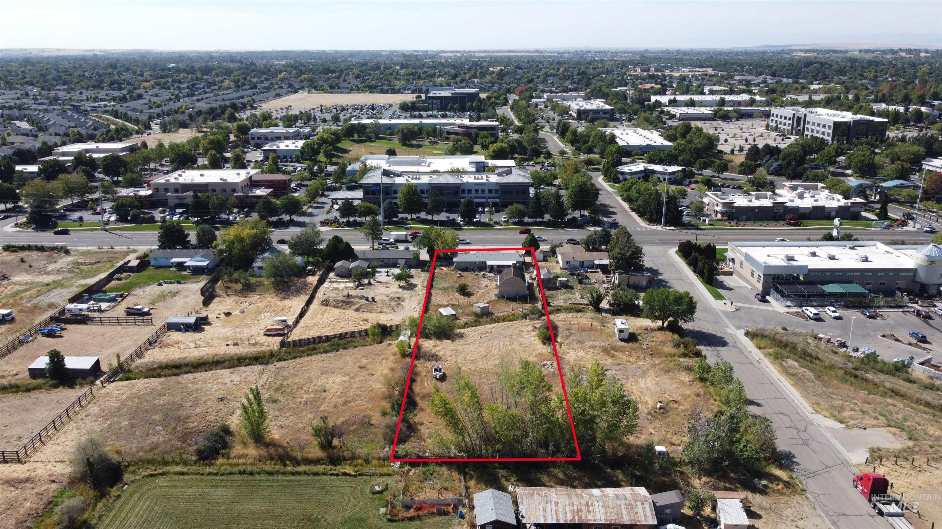 Aerial view of a dry parcel outlined in red, with a small building near the road and commercial buildings nearby.