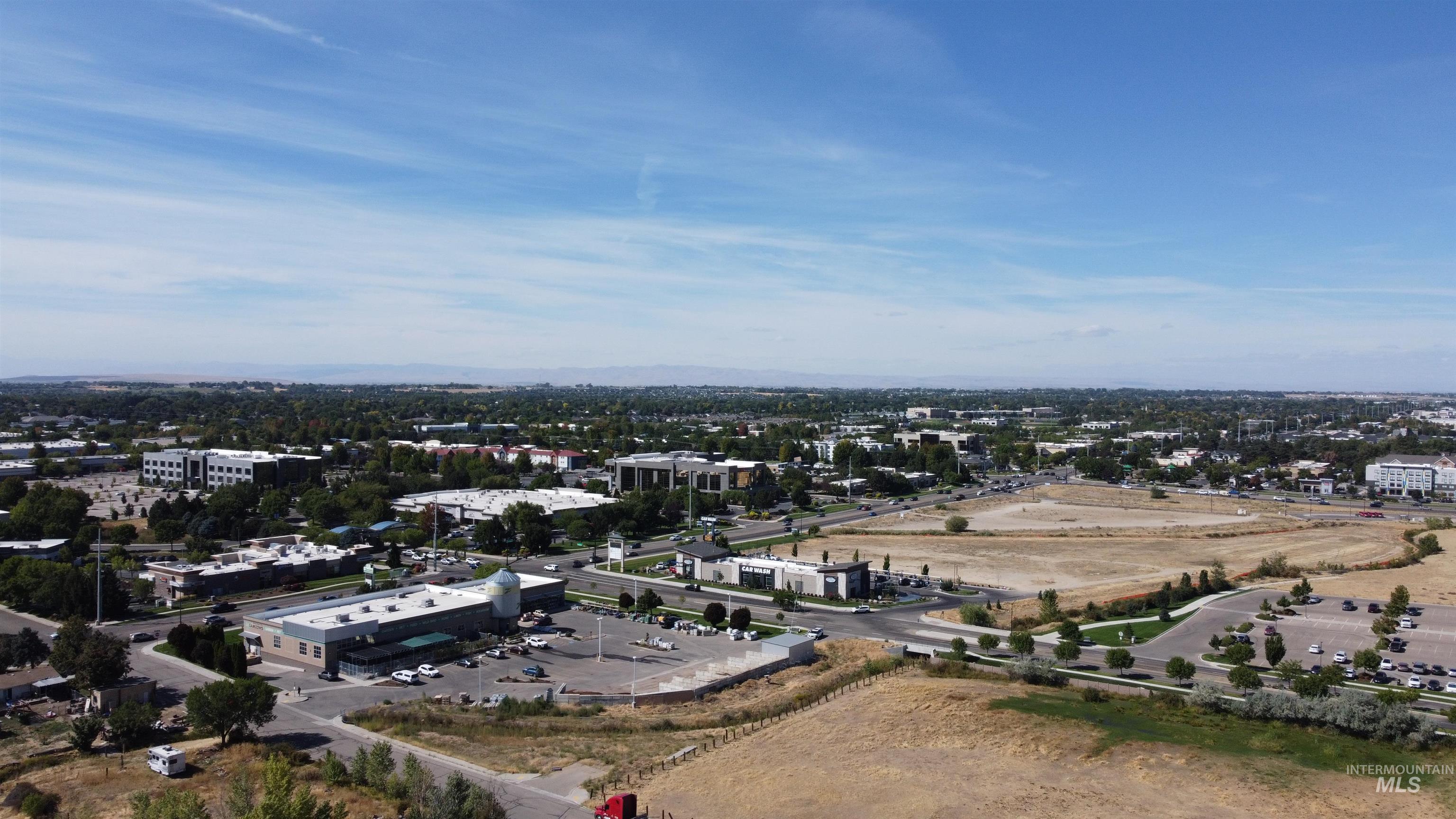 Aerial view of a vacant parcel bordered by roads and commercial buildings.