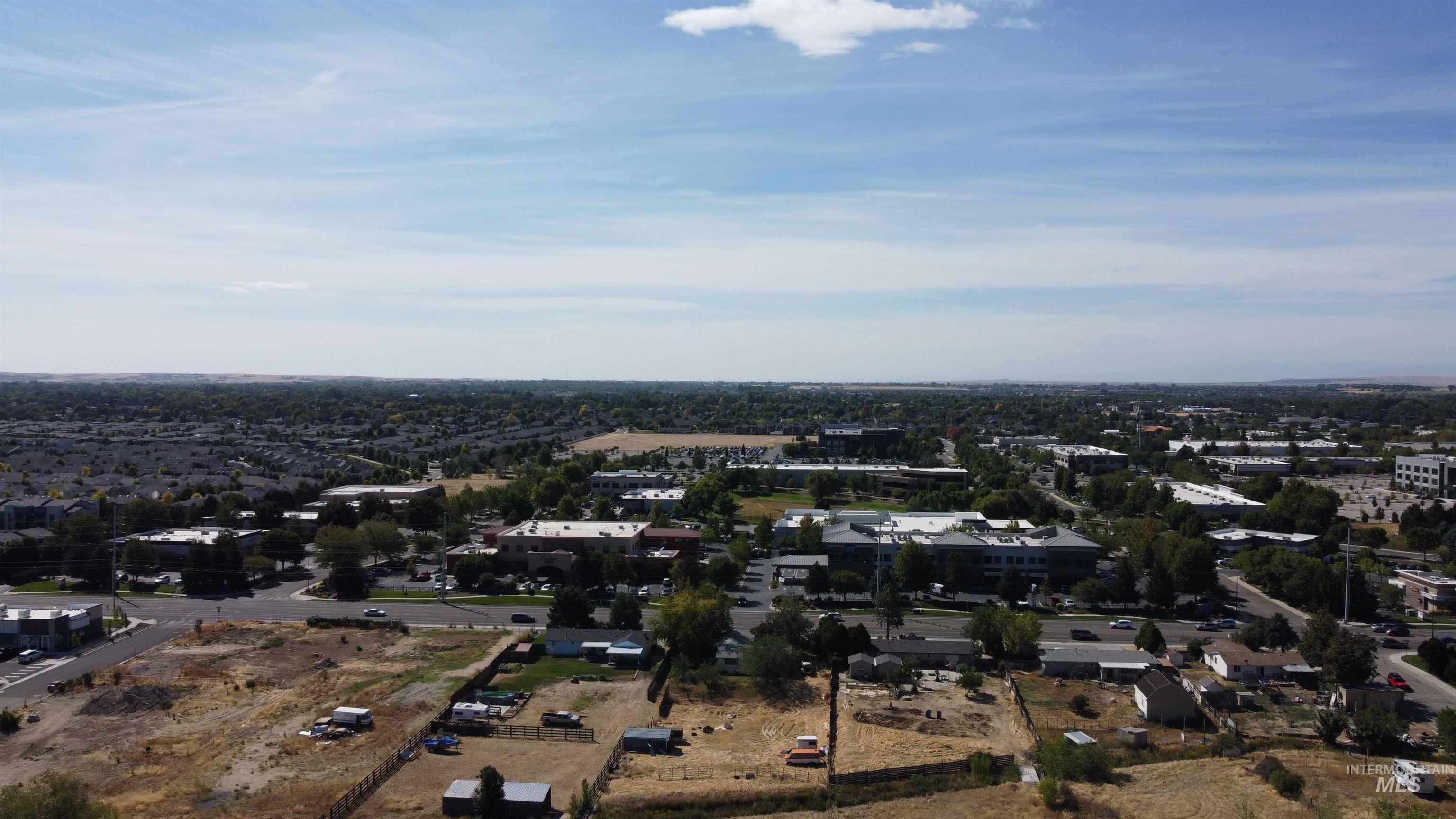 Aerial view of open fenced land beside residential and commercial buildings.