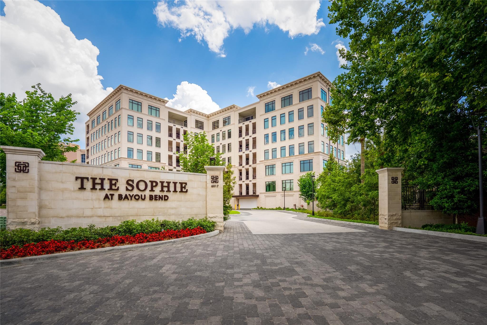The Sophie at Bayou Bend condominium behind its stone entrance sign and landscaped driveway.