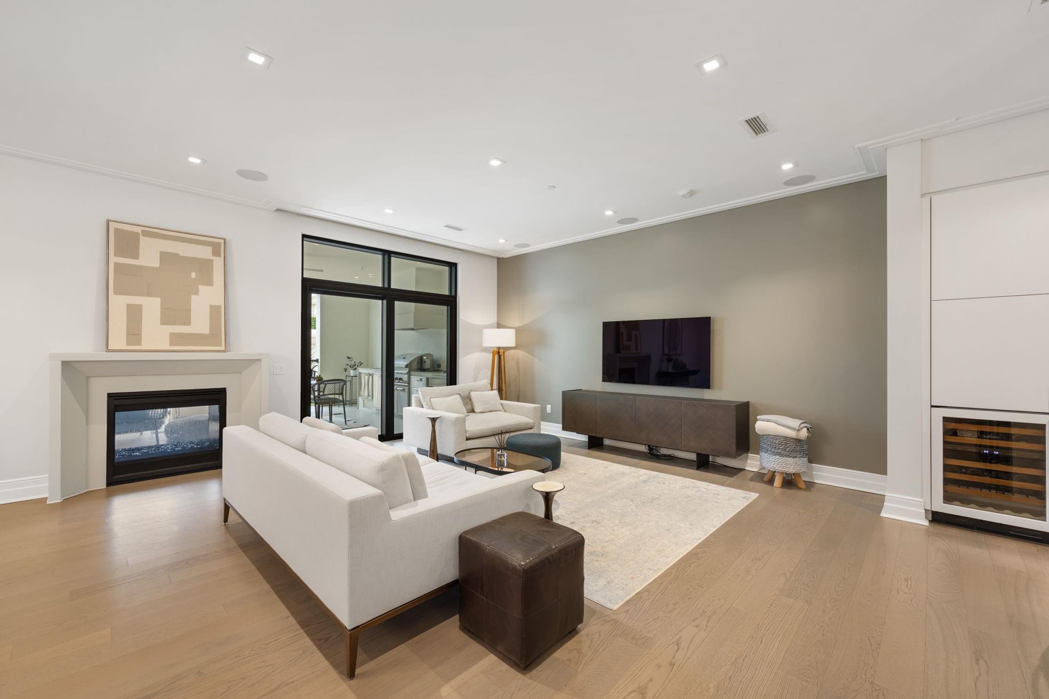 Staged living room with white sofas, a fireplace, and glass doors to a patio.