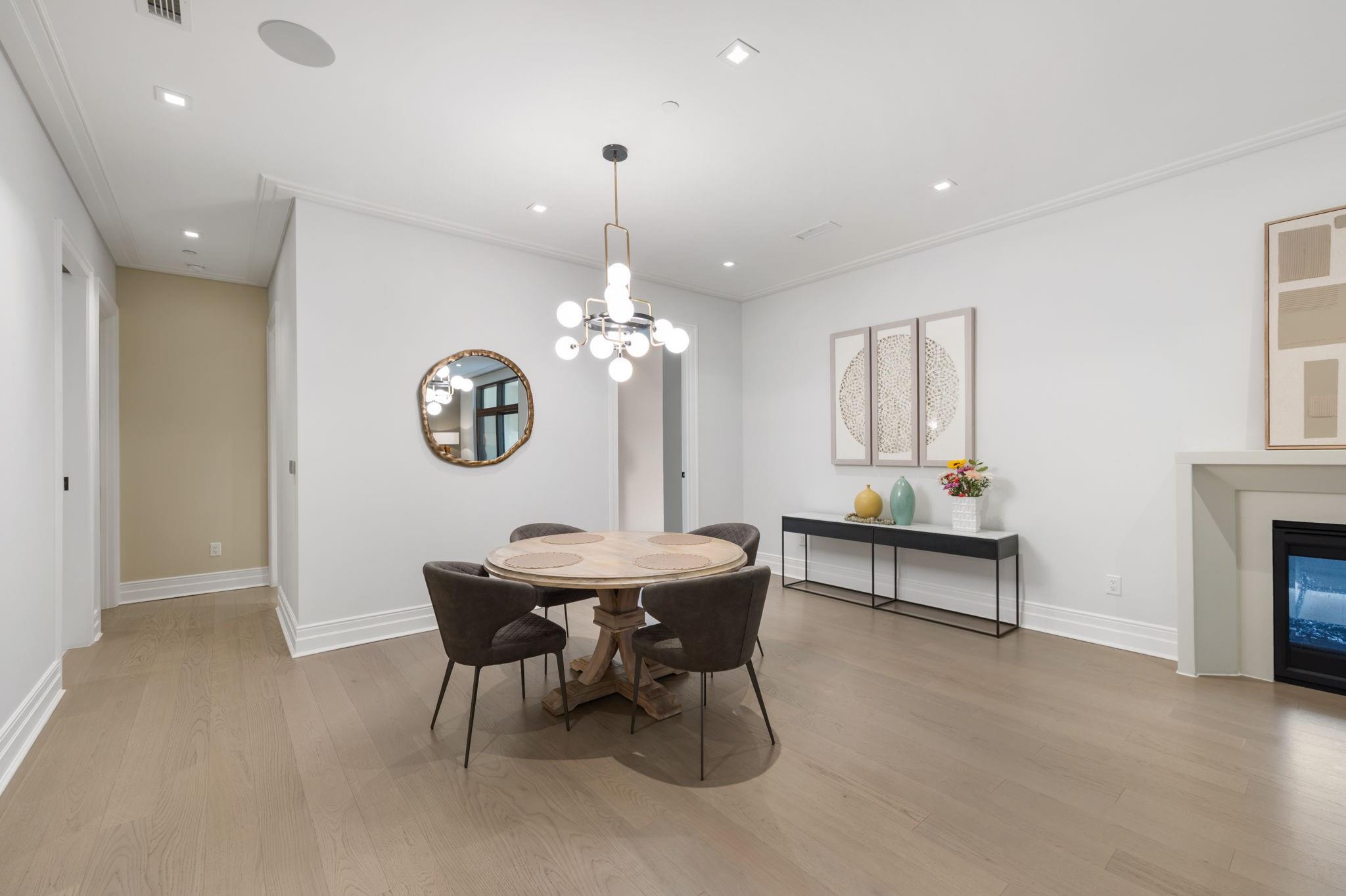 Dining room with a round wood table, dark chairs, globe chandelier, and fireplace.