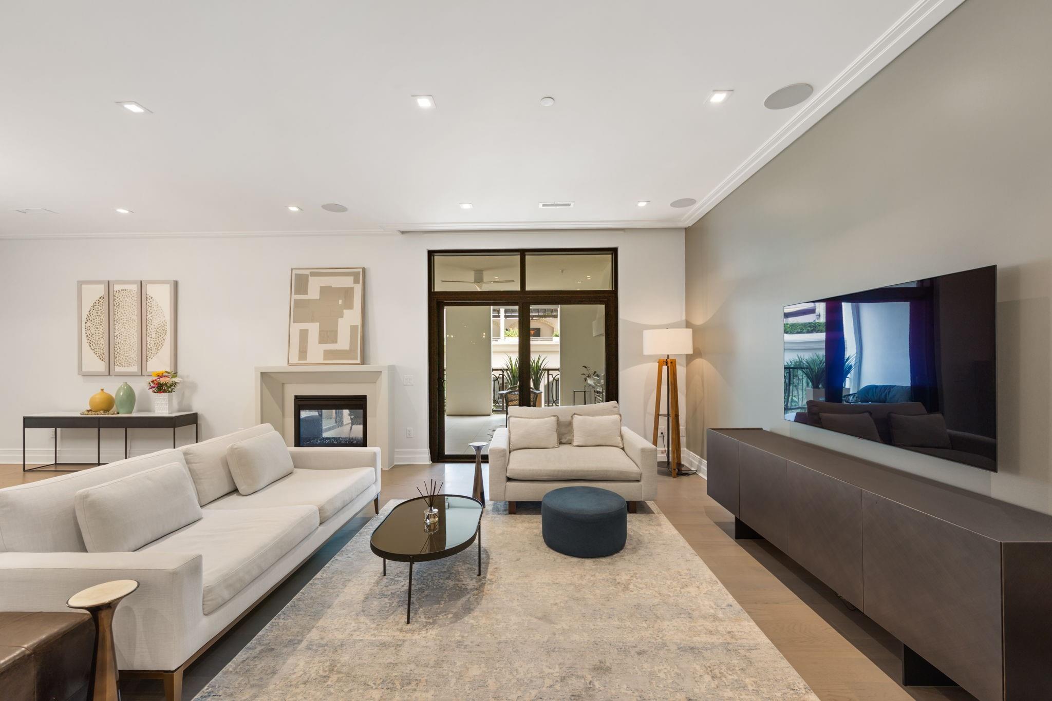 Living room with white sofas, a fireplace, and glass doors to a balcony.