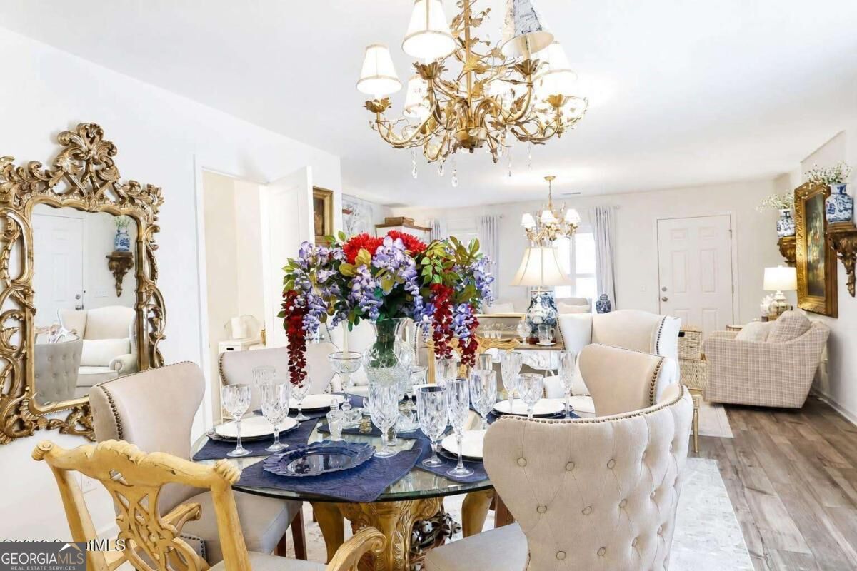 Dining room with a glass table set with crystal, colorful flowers, and ornate gold furnishings.