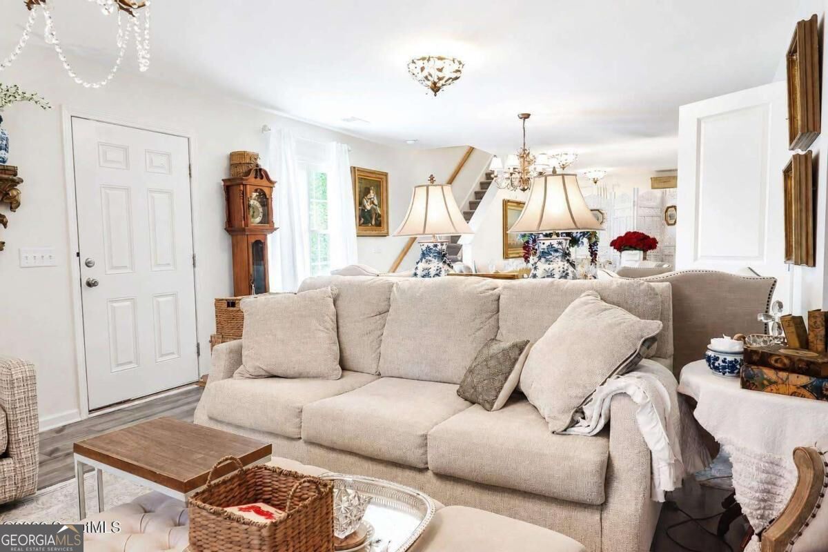 Living room with a beige sofa, wood coffee table, grandfather clock, and staircase.