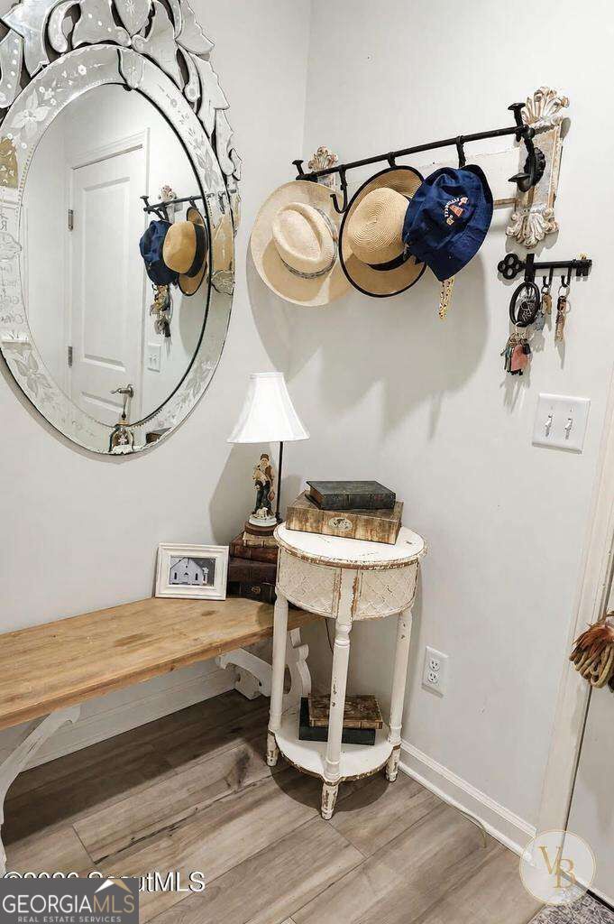 Entryway with a wooden bench, ornate oval mirror, and wall hooks holding hats and keys.