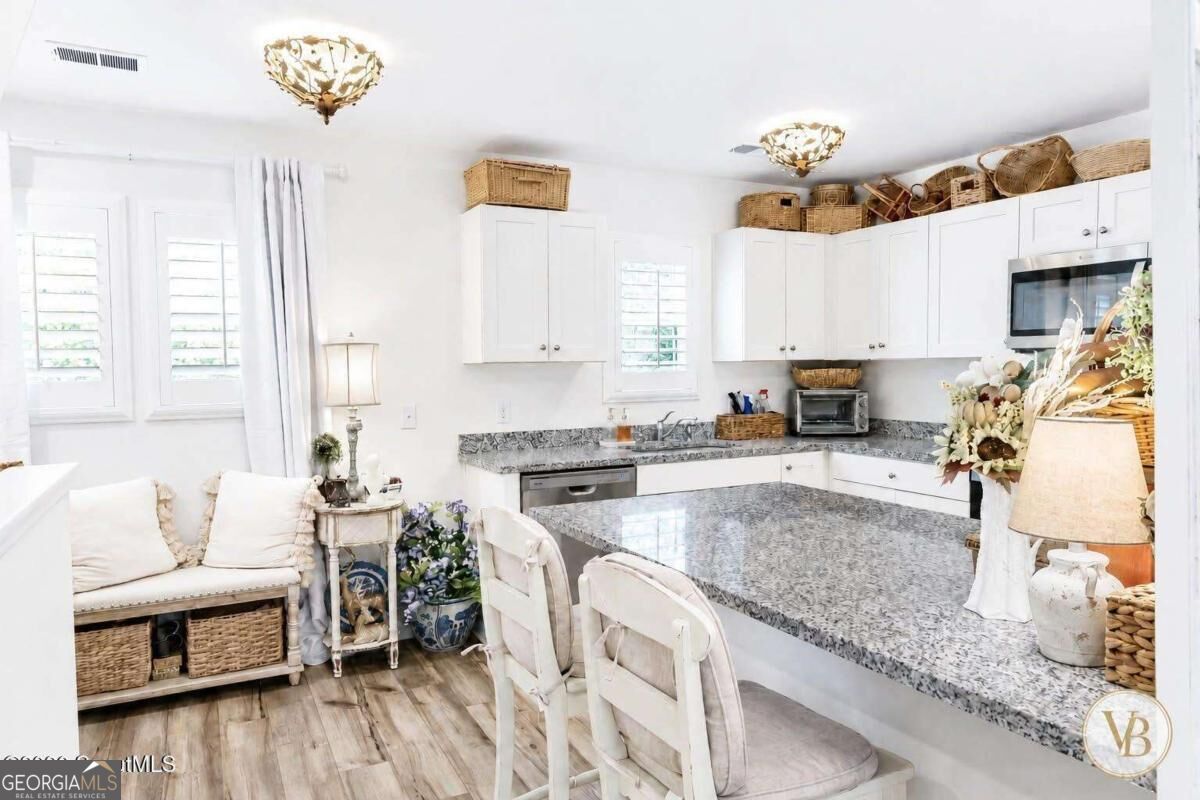 Bright white kitchen with a granite island, white cabinetry, and a cozy seating nook.