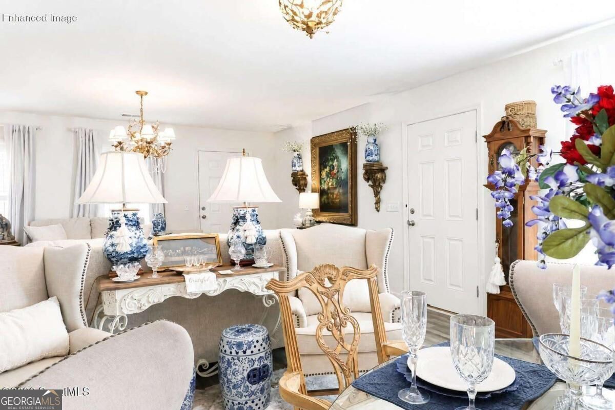 Furnished living and dining area with cream seating, blue-and-white porcelain lamps, and ornate wooden furniture.