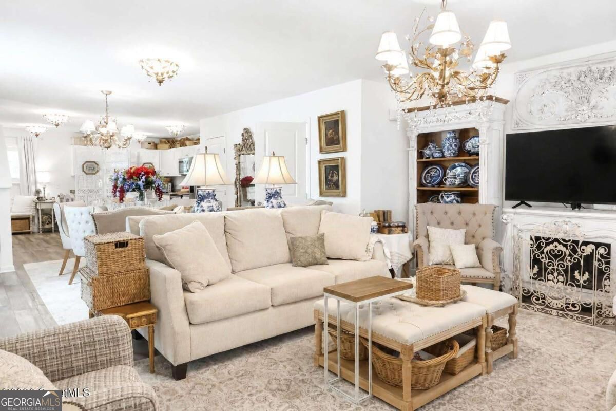 Living room with a cream sofa, ornate white fireplace, and open kitchen in the background.