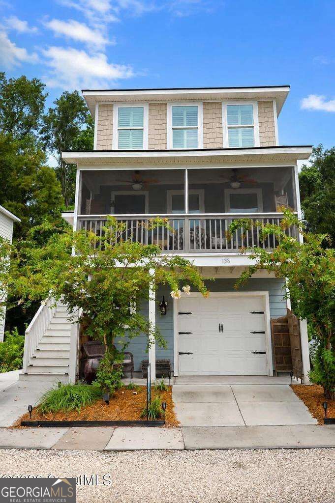 Two-story house with a screened porch, white staircase, and garage beneath the porch.