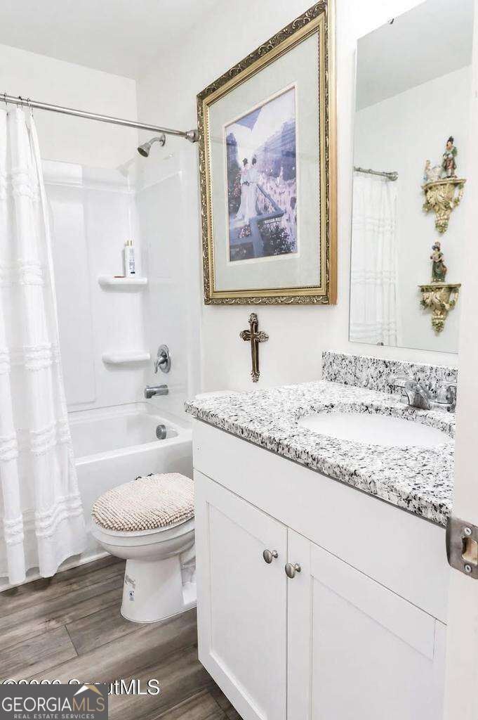 Bathroom with a speckled granite vanity, white tub and shower, and framed wall art.