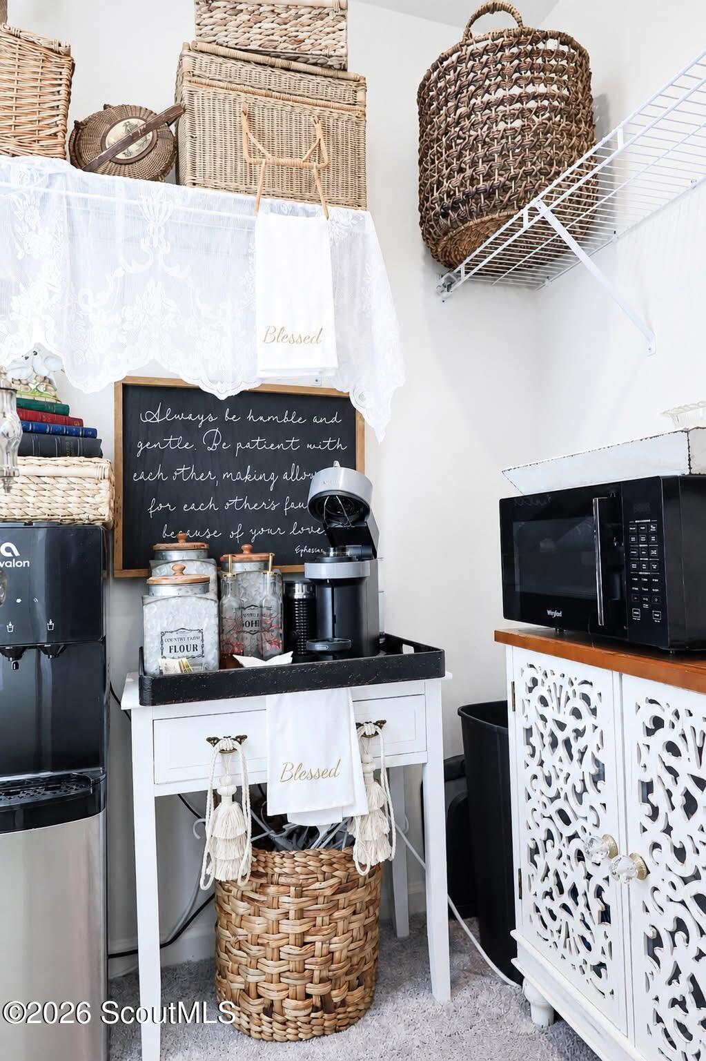 Kitchen coffee station with a black coffee maker, woven baskets, and ornate white cabinet.