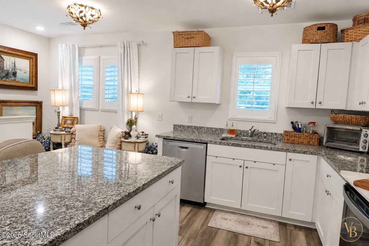 Kitchen with white cabinets, granite countertops, a large island, and stainless steel appliances.