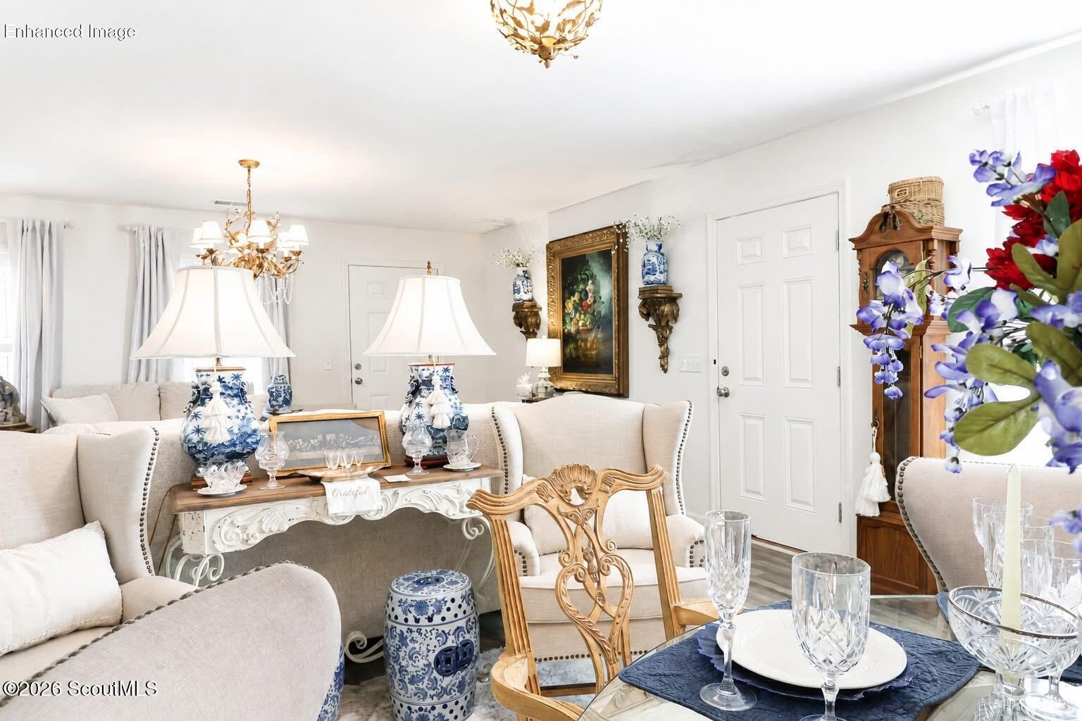 Furnished living room with cream seating, ornate wood furniture, and blue-and-white porcelain accents.
